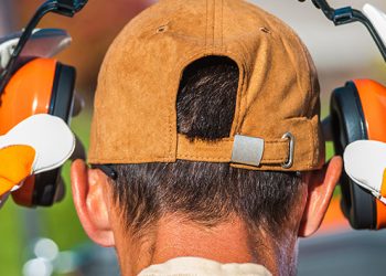worker putting on headphones to reduce noise exposure