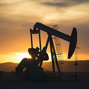 A pumpjack at an oil drilling site at sunset.