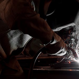 Cropped Image of Manufacture Worker Welding Metal With Sparks at Factory