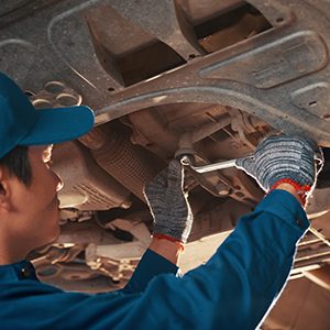 Car mechanic tightening nut with spanner on car bottom