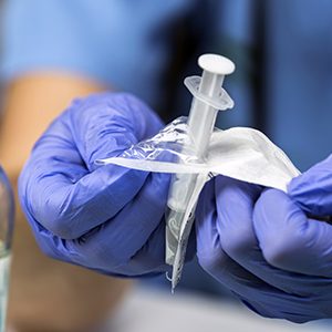 Nurse opens a new syringe in a hospital, conceptual image