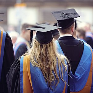 Graduates at university graduation  ceremony wearing mortarboard and gown