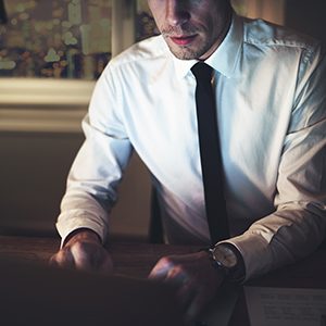 Horizontal crop shot of a lawyer using the laptop sitting at workplace in the evening.