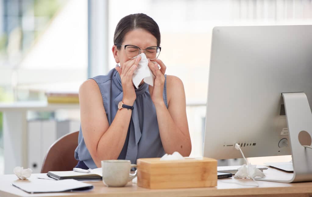 Sick worker at desk sneezing