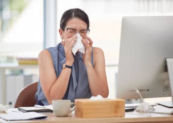 Sick worker at desk sneezing