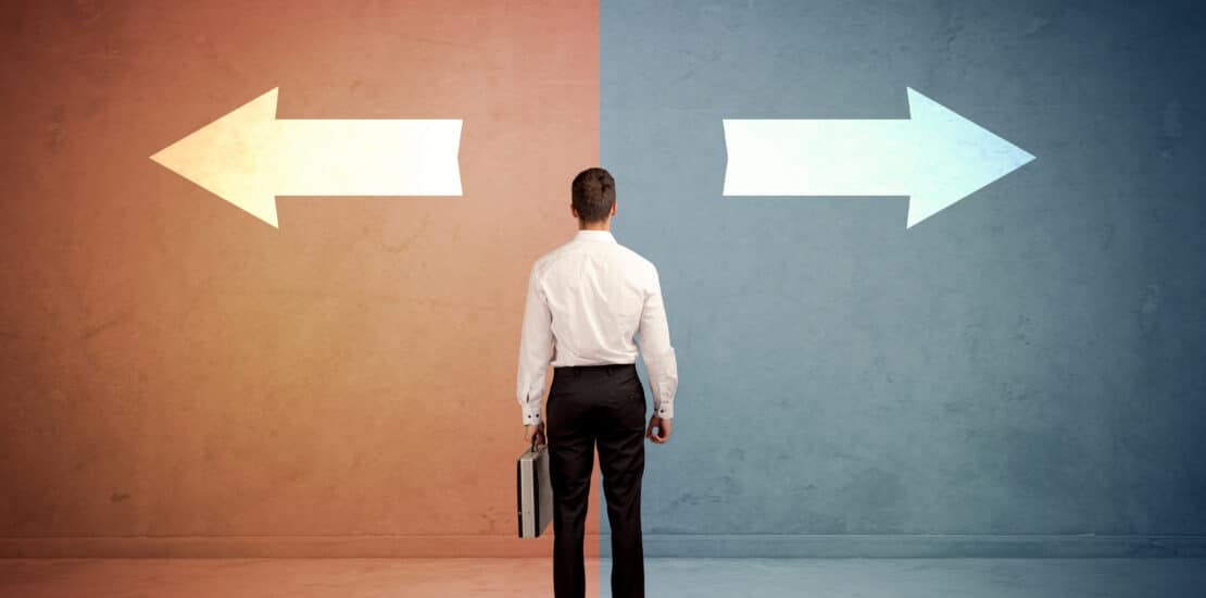 Person facing a wall with arrows pointing in opposite directions, representing different career paths or choices.