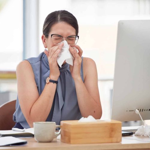 Sick worker at desk sneezing